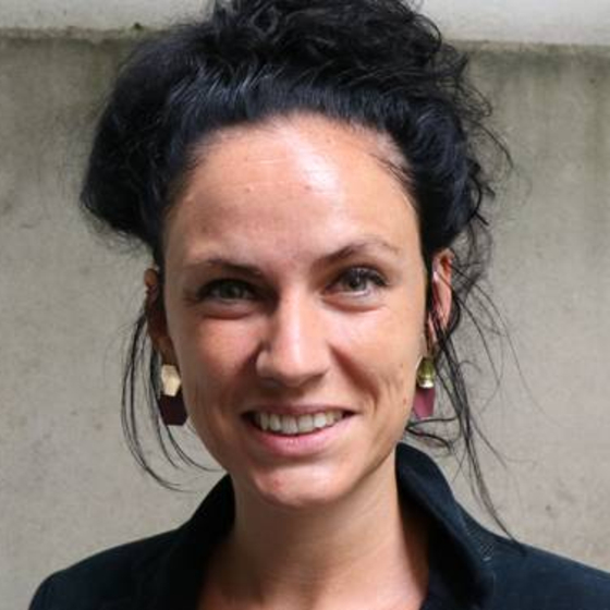 Porträt Katharina Mosene. Ausschnitt von Kopf bis Schulter mit einfarbigen Hintergrund. Sie blickt frontal in die Kamera. 
