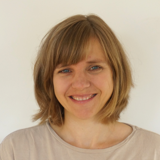Porträt Doktorin Dorothée Hefner. Ausschnitt von Kopf bis Schulter mit einfarbigen Hintergrund. Sie blickt in die Kamera und lächelt.