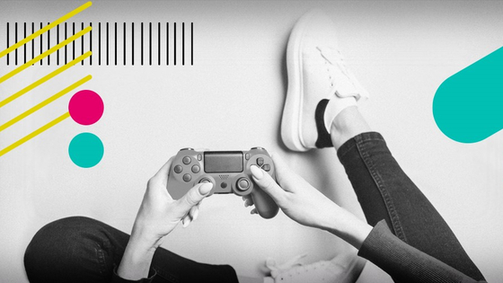 Bild in schwarz und weiß mit eingefügten bunten Gestaltungselementen. Es sind die Hände und die Füße einer Person zu sehen, die sitzend einen Playstation Controller hält. 