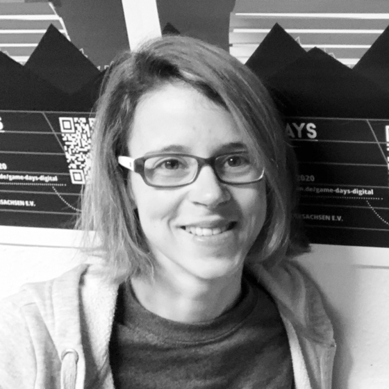 Porträt Sarah Weber. Ausschnitt des Bildes von Kopf bis Schultern. Sie blickt in die Kamera und lächelt. Sie befindet sich vor einer Wand. 