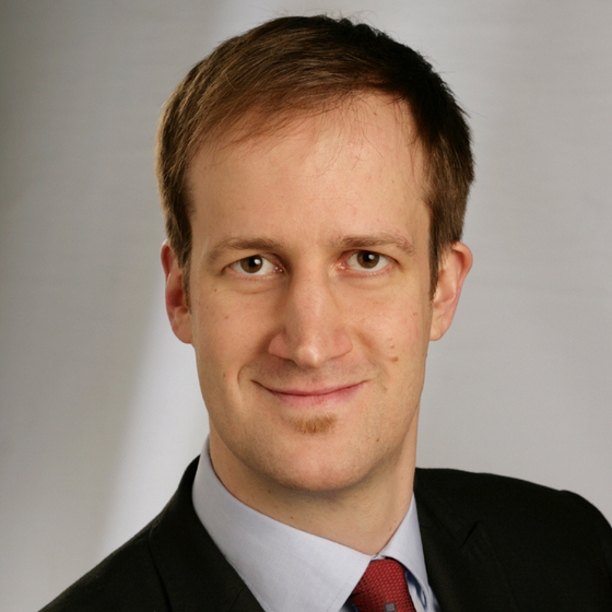 Porträt Professor Doktor Tonio Oeftering. Ausschnitt von Kopf bis Schulter mit einfarbigen Hintergrund. Er blickt in die Kamera.